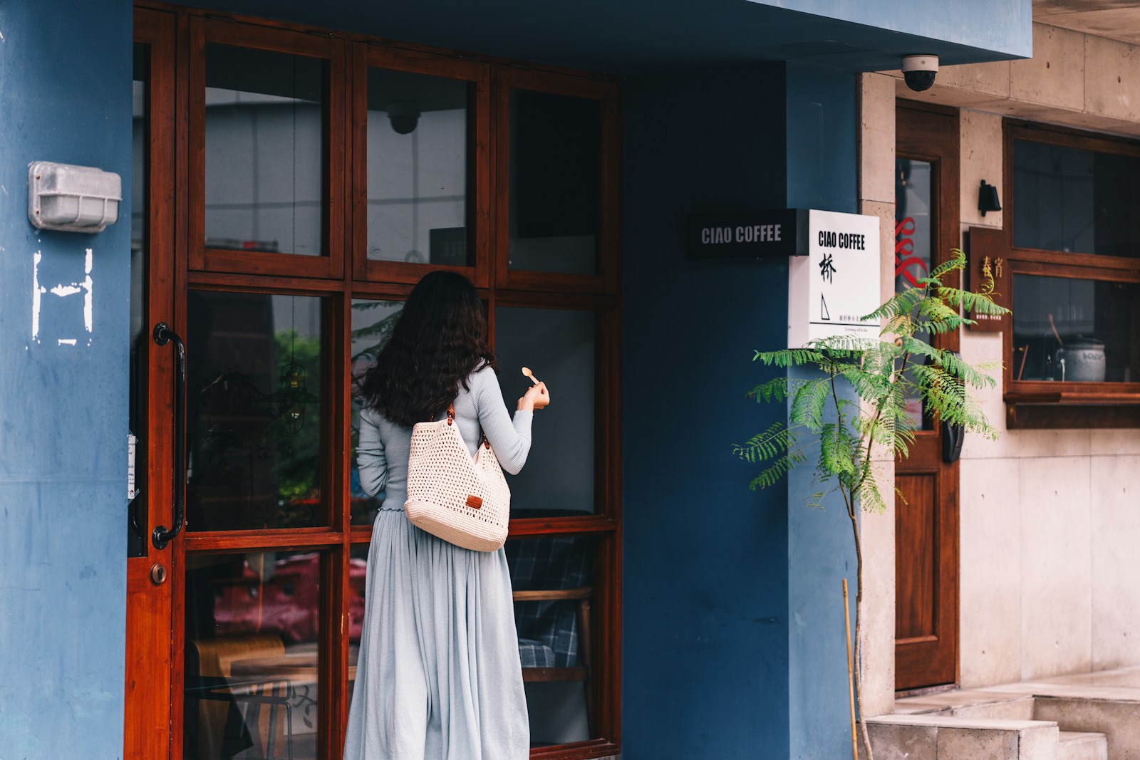 Woman enters a blue building.