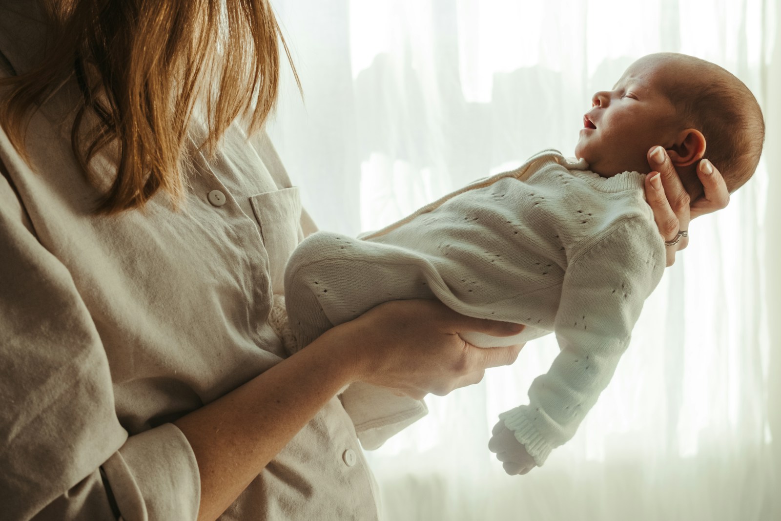 Mother holding her newborn baby near a window