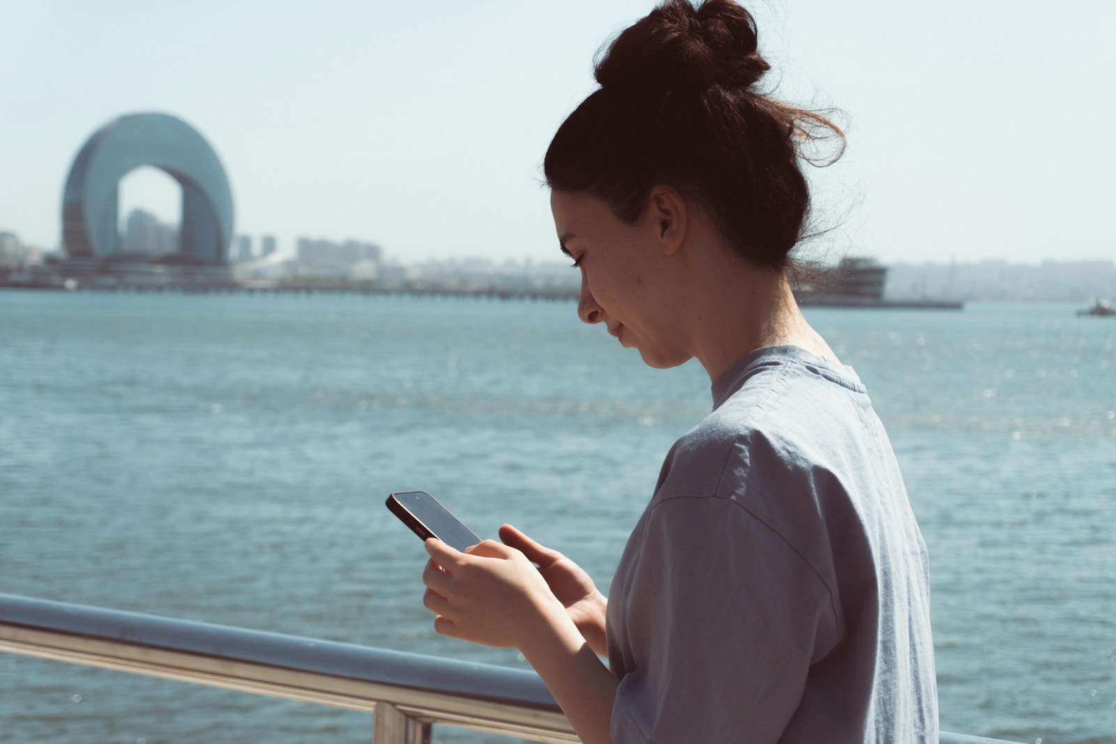 Woman uses her phone by the water.