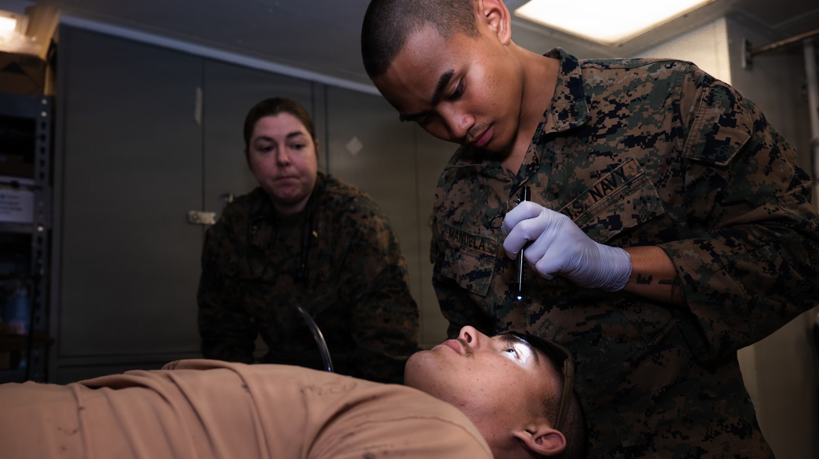 Marines practice medical procedures on a simulated patient.