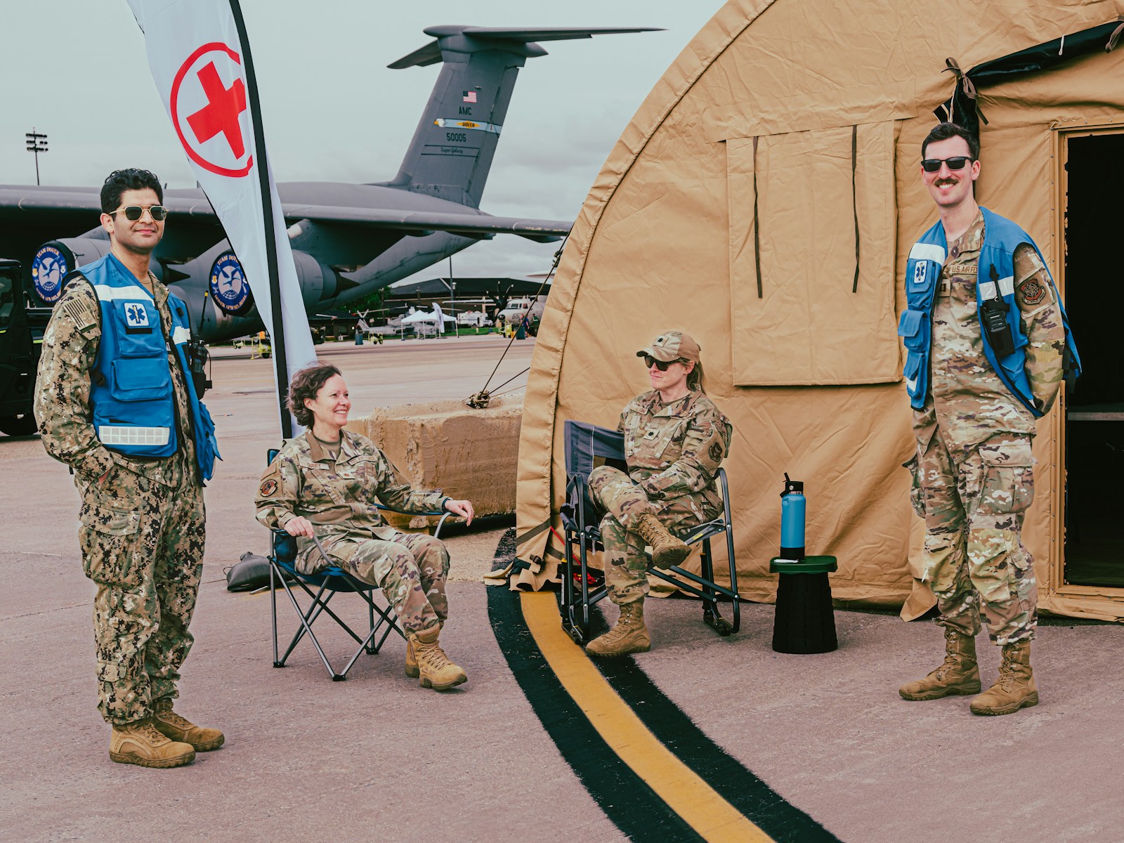 Military personnel pose near a medical tent and plane.