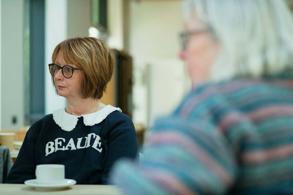 a woman sitting at a table with a cup of coffee
