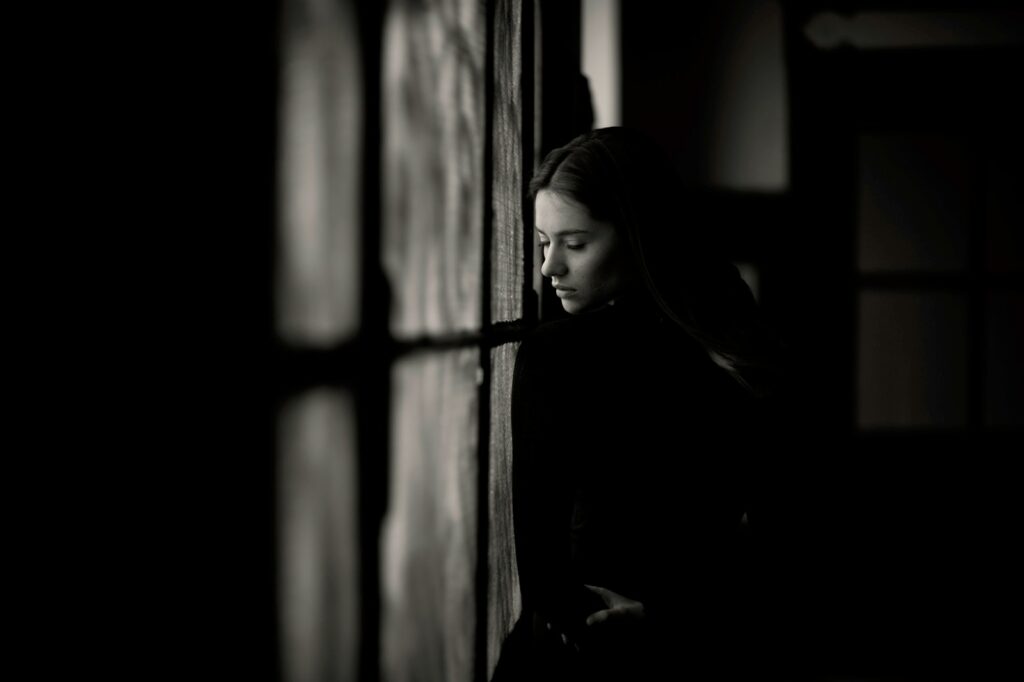 a woman leaning against a wall in a dark room