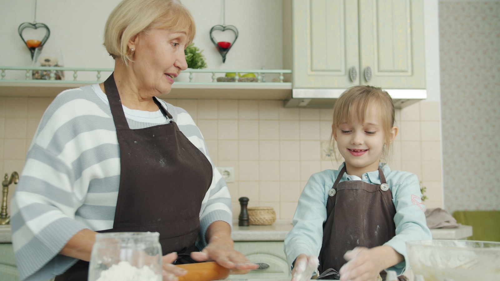 Grandmother and granddaughter baking together in kitchen.
