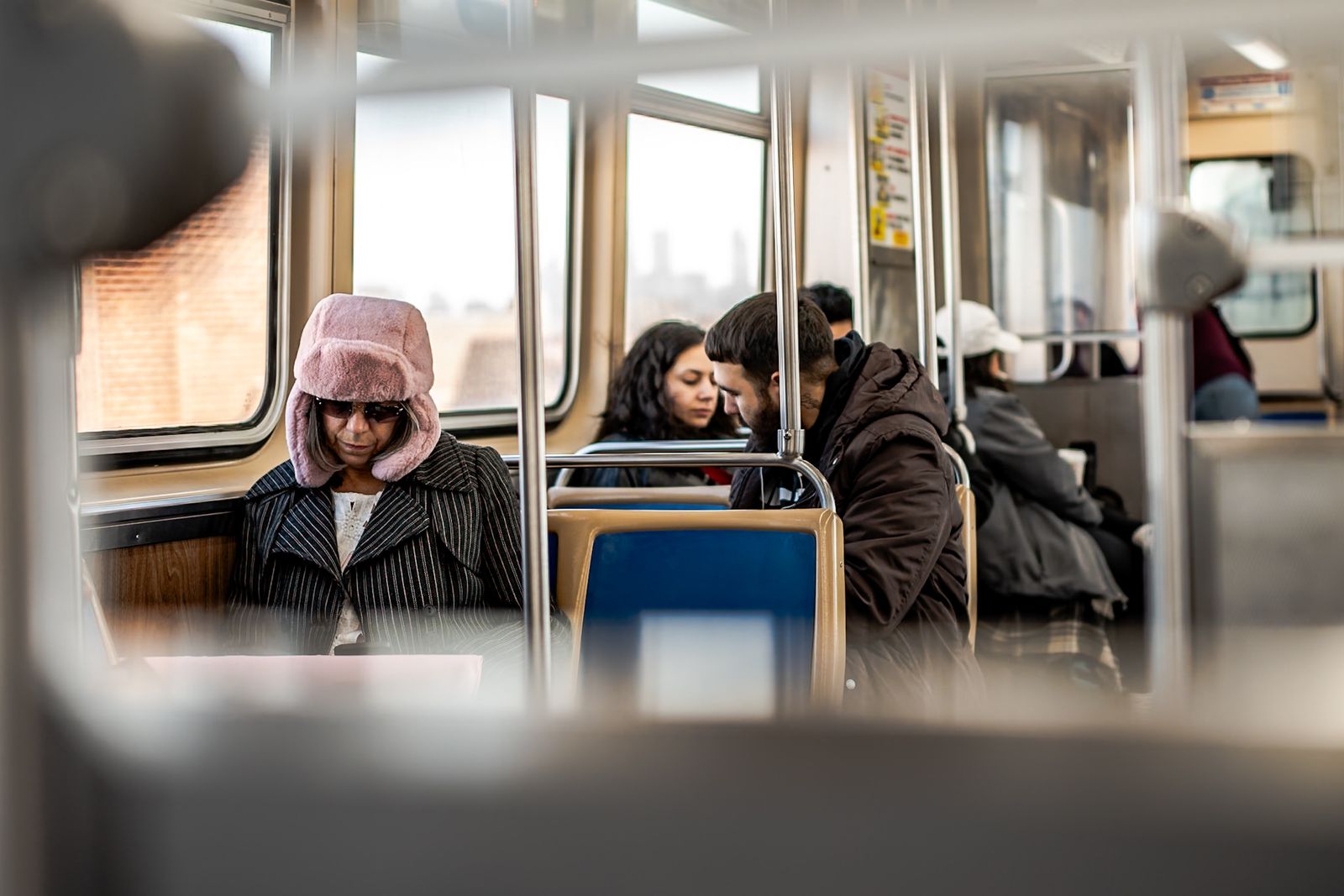 Passengers wearing winter coats and hats on a train during a city commute.
