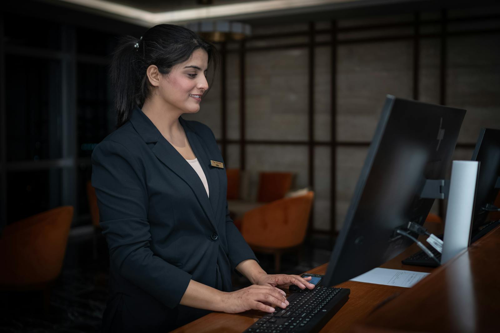 A female receptionist working at a hotel front desk in Islamabad, Pakistan.