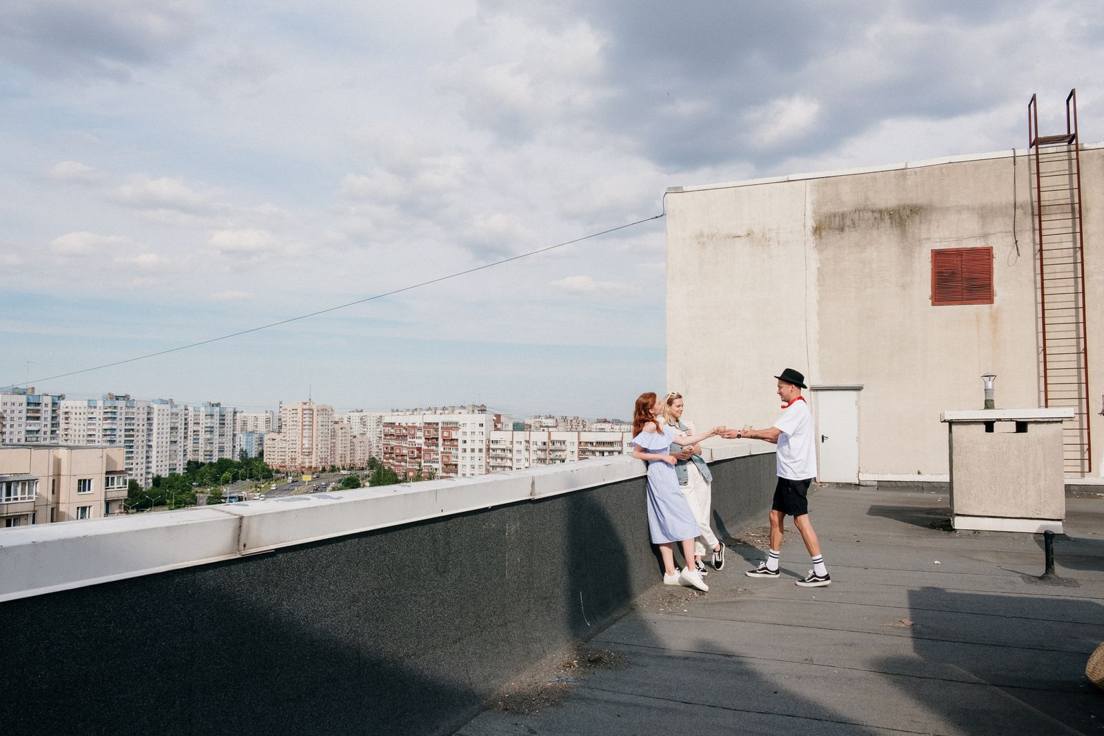 A group of young adults hanging out on a city rooftop enjoying a sunny day.