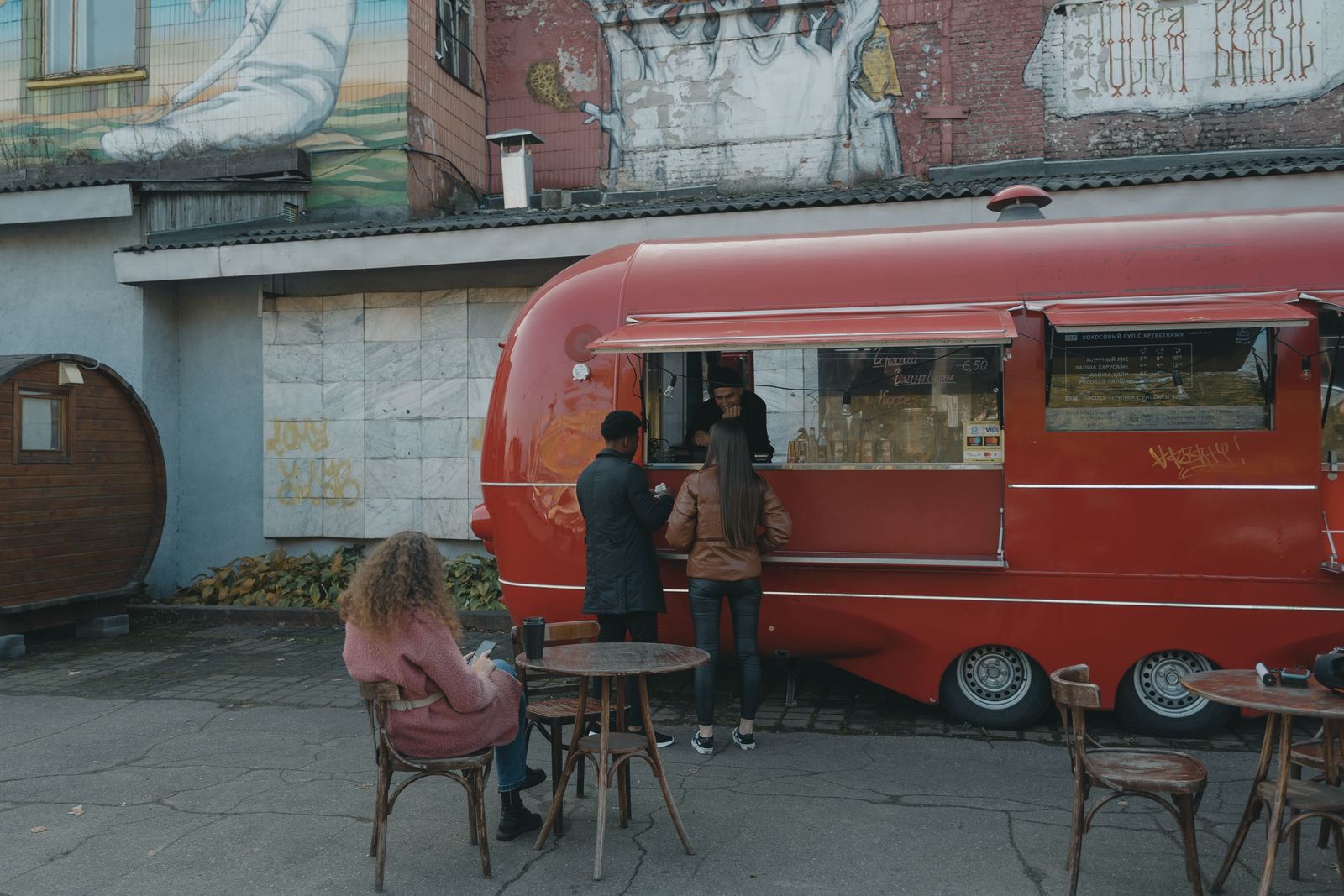 A vibrant urban scene with a red food truck serving people on the street, offering an authentic street food experience.