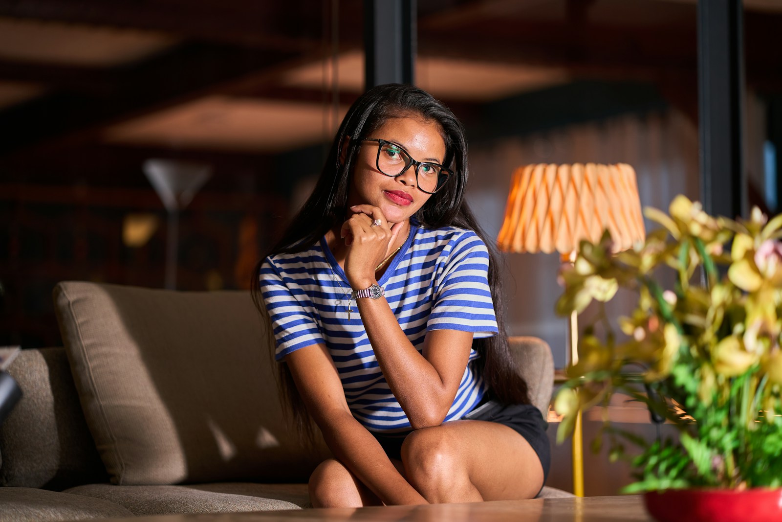 A woman with glasses sits on a couch.