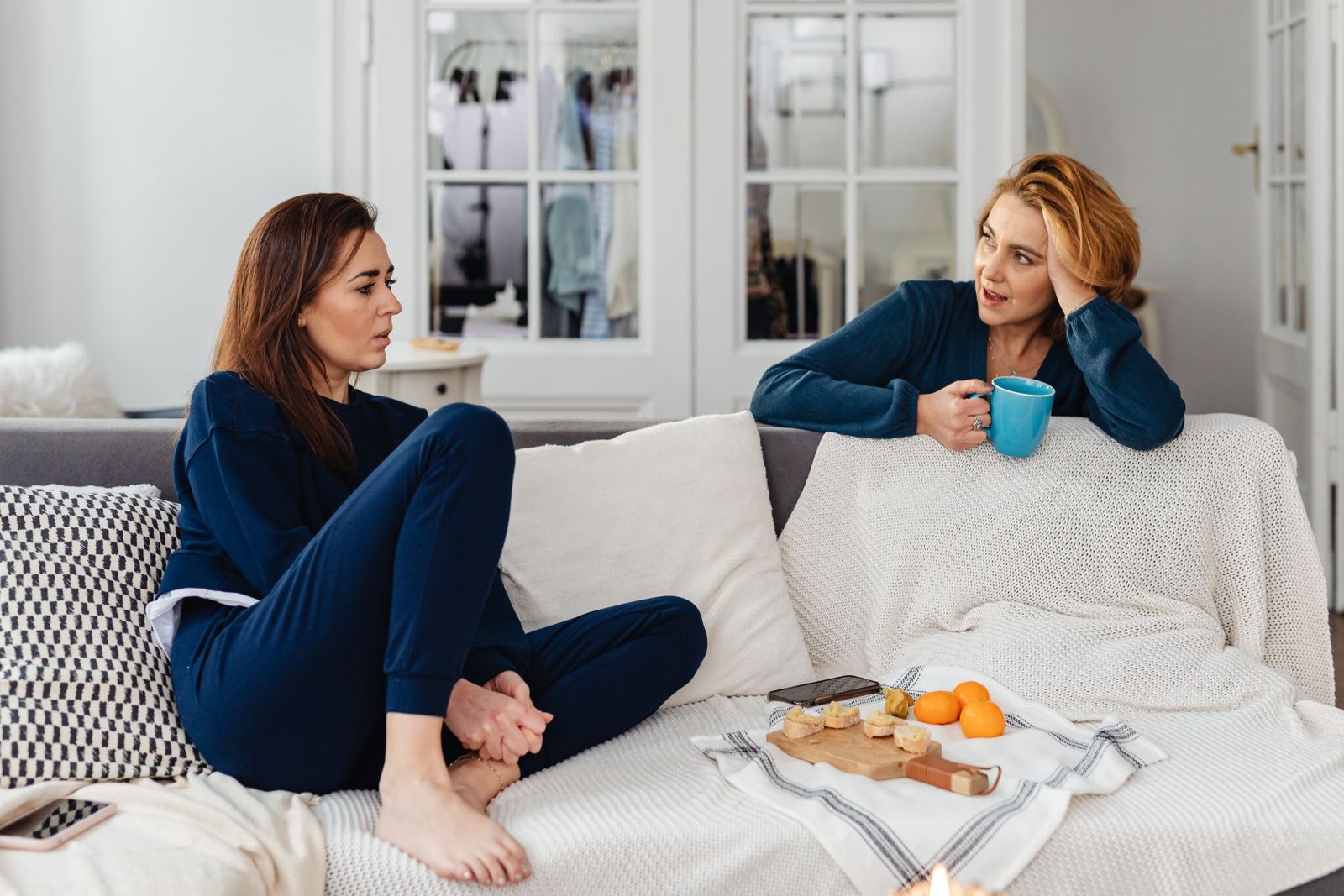 Two women having a relaxed conversation on a comfortable indoor couch.