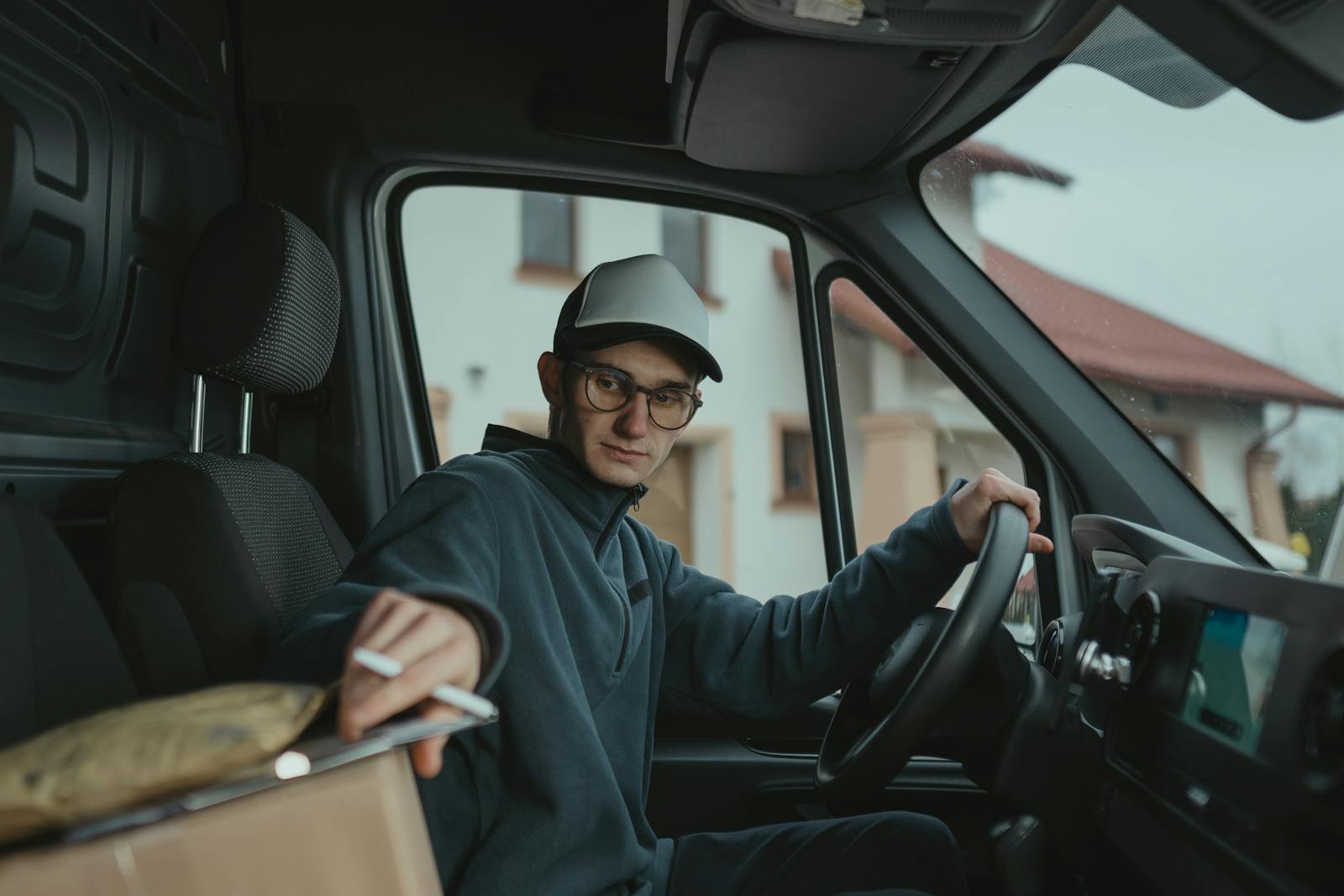 Young delivery driver inside a van preparing to deliver a package, showcasing logistics work.