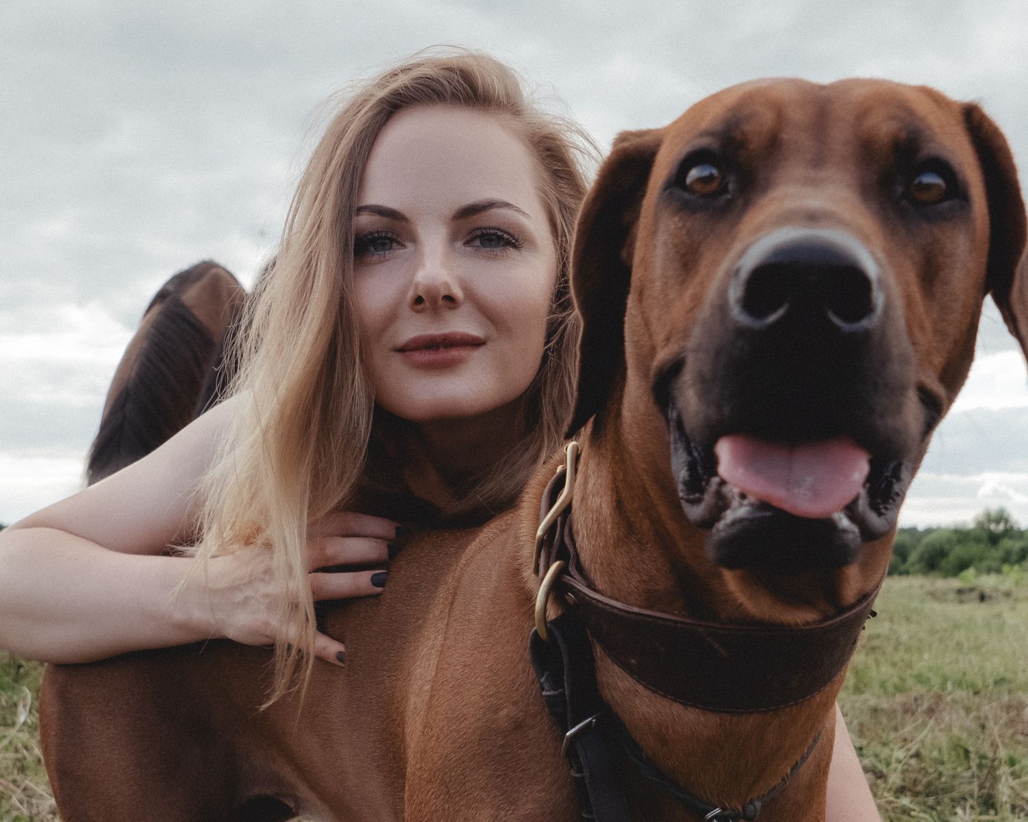 A happy young woman embracing her dog on a sunny day outdoors.