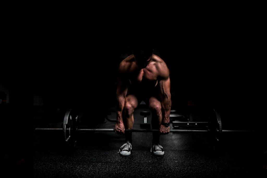 shirtless man lifting barbell in gym
