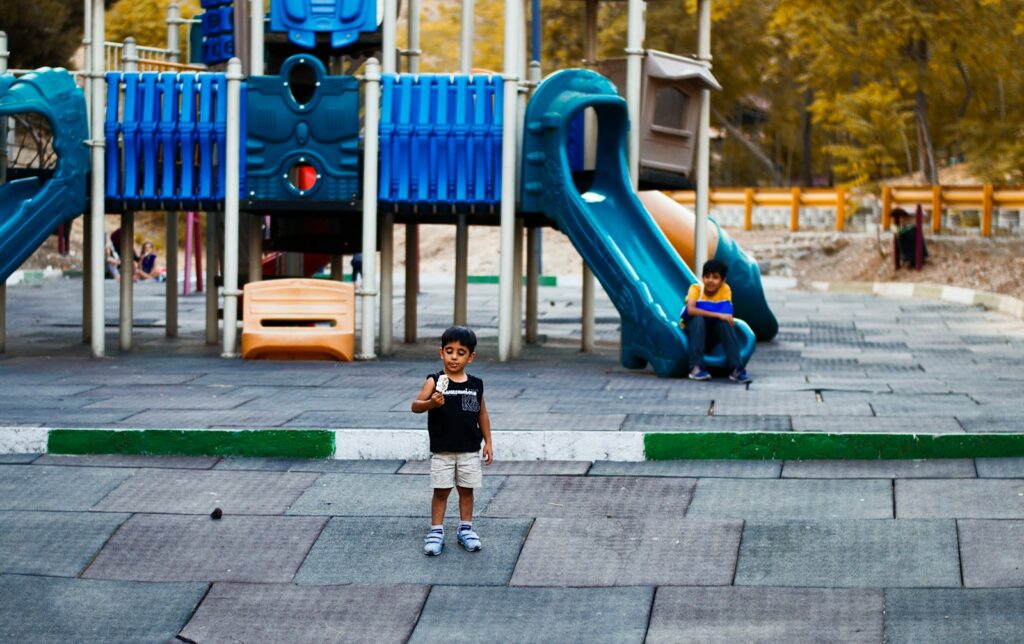 girl in black t-shirt standing beside blue slide