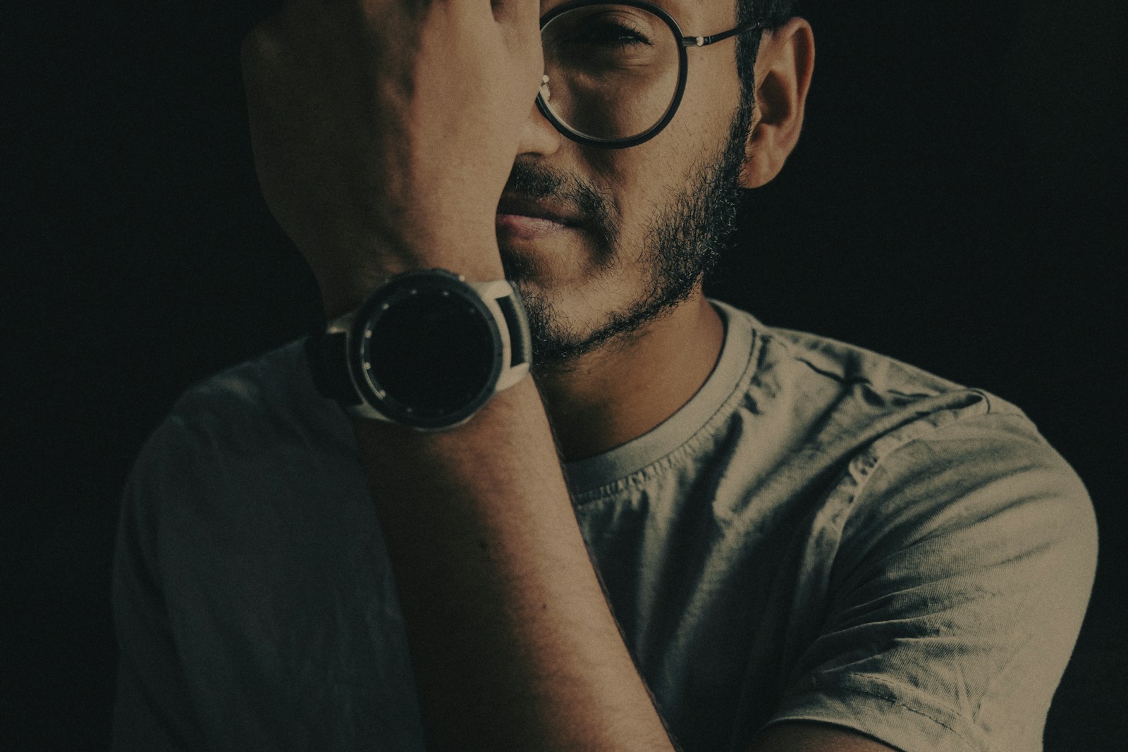 man in gray crew neck shirt wearing black framed eyeglasses holding black camera
