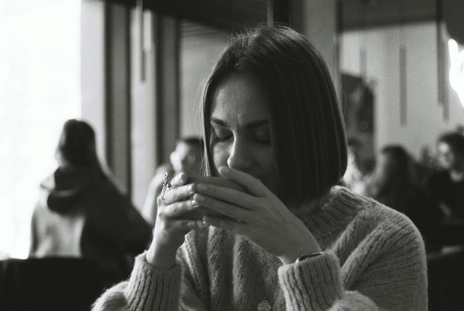 Woman enjoys a warm drink, looking peaceful.