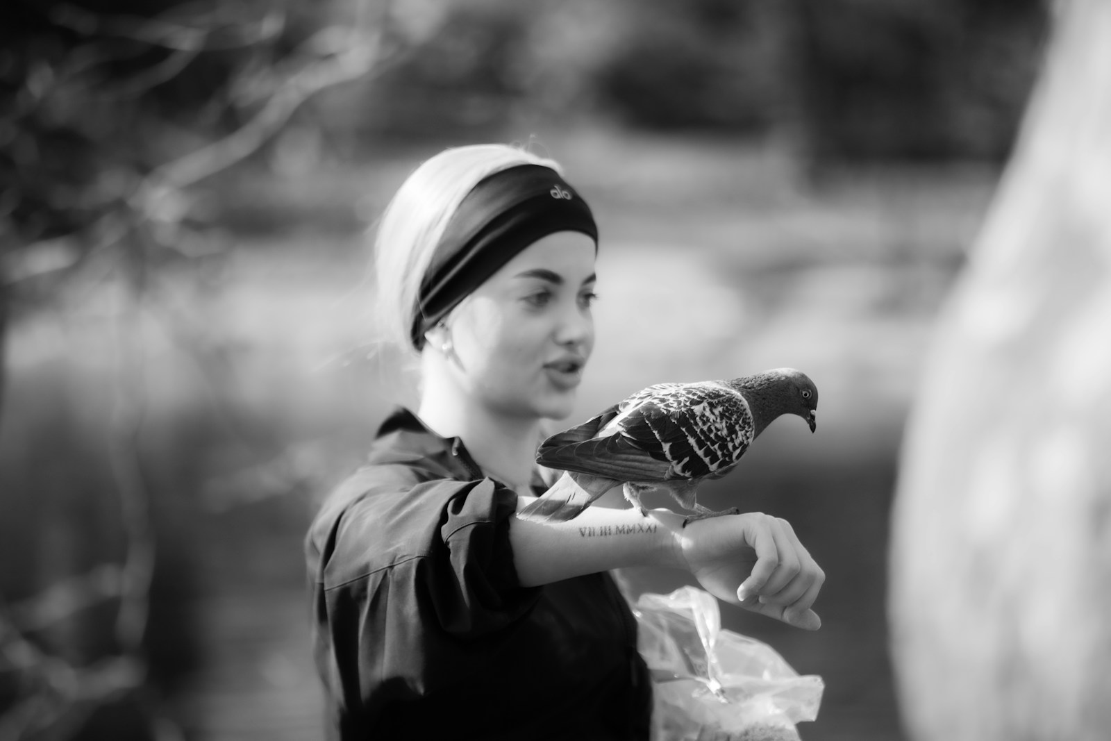 A young woman with a pigeon perched on her arm.