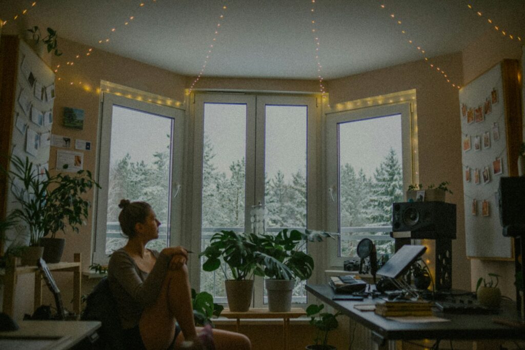 Woman sitting by window with snowy trees outside