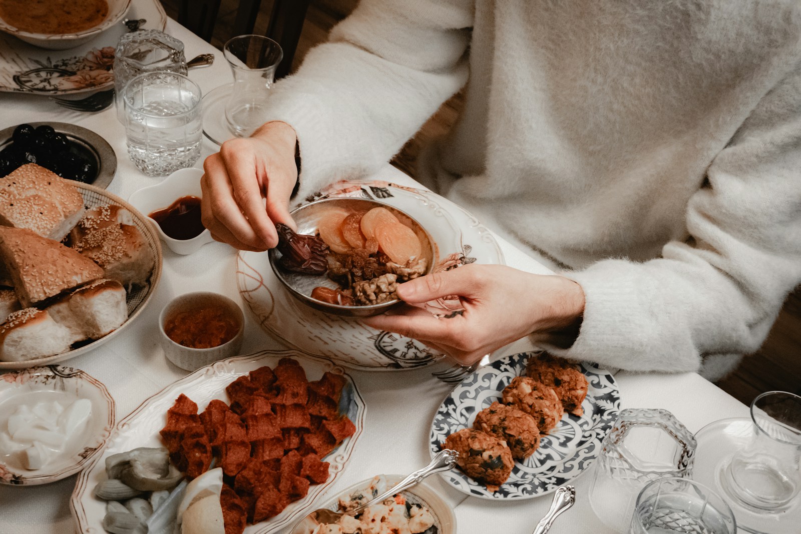 A person eating a meal with many dishes on table