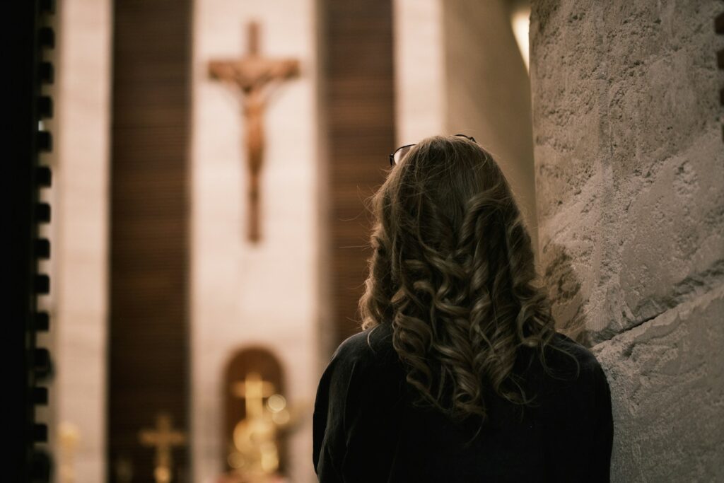 Woman praying before a crucifix in church