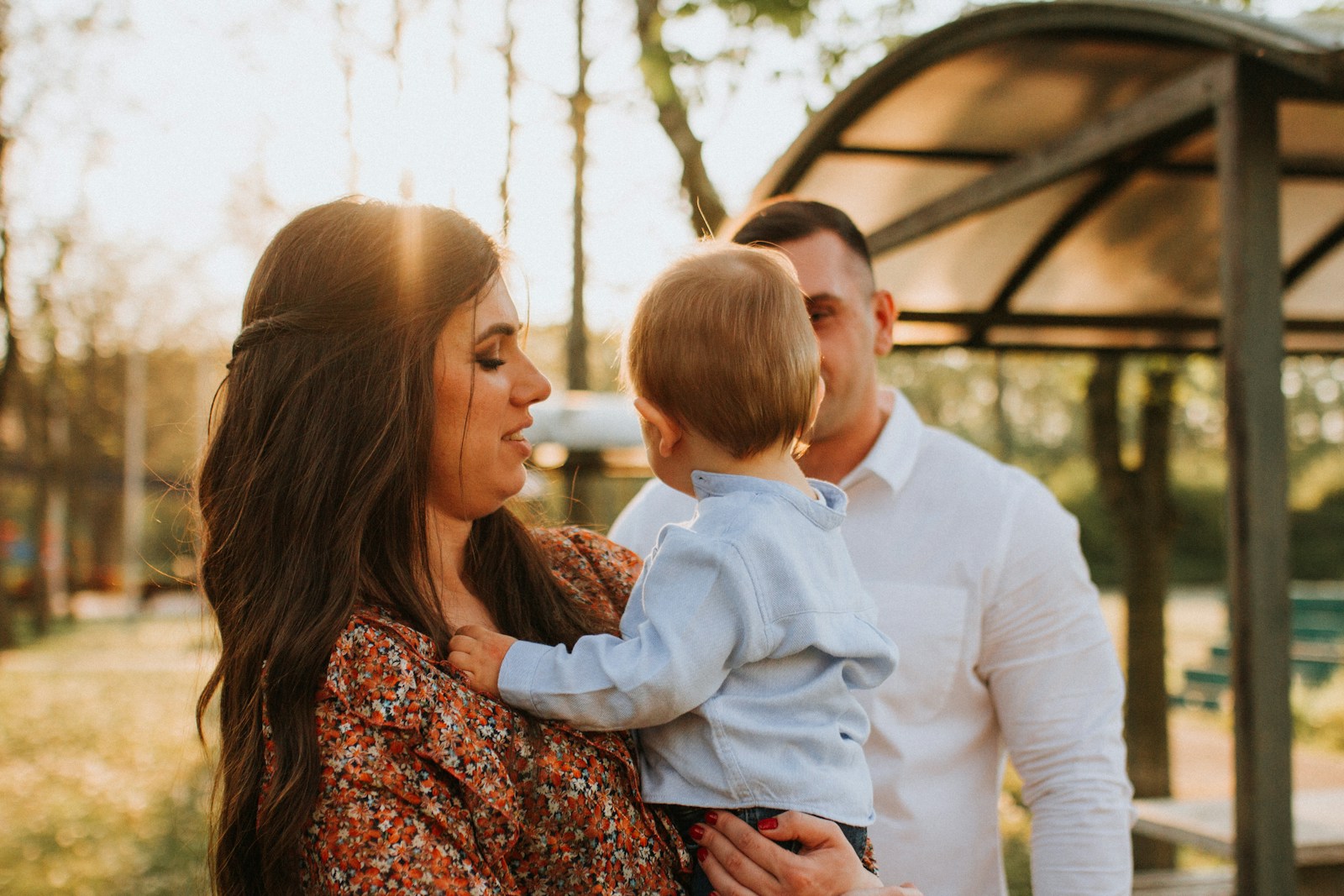 a man and woman holding a baby in a park
