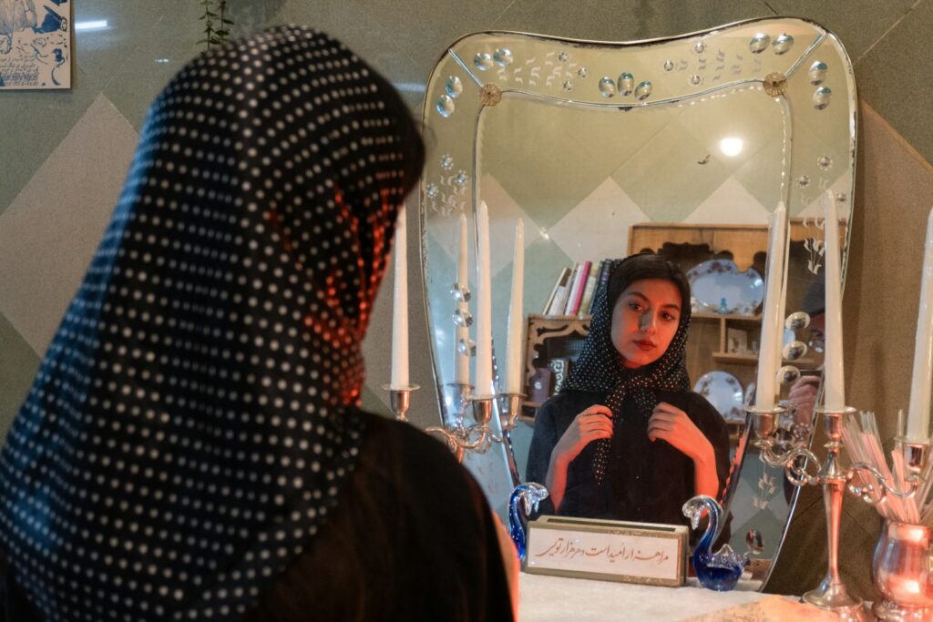 Woman adjusting hijab in front of ornate mirror