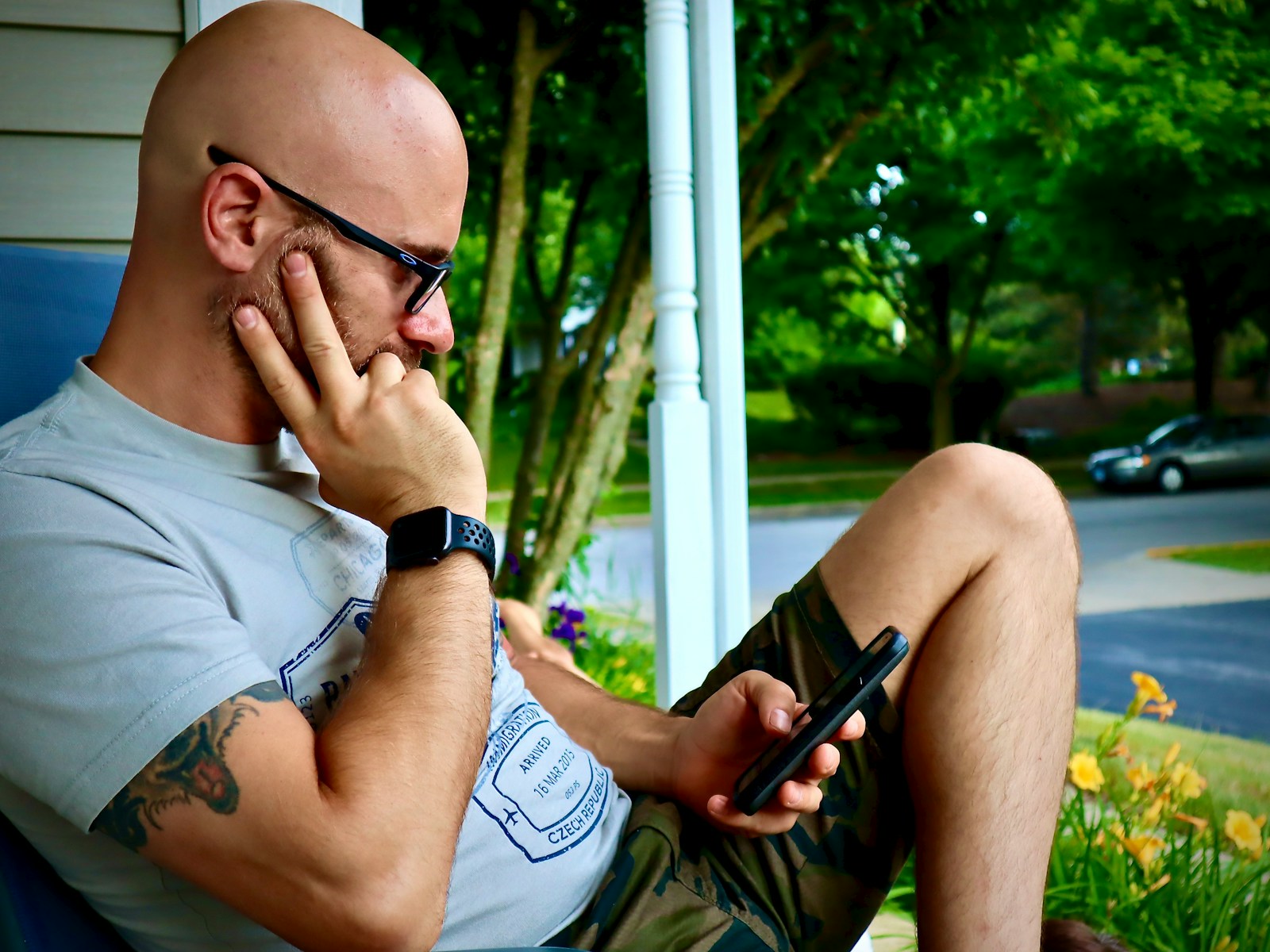 man in white tank top wearing black framed eyeglasses holding black smartphone