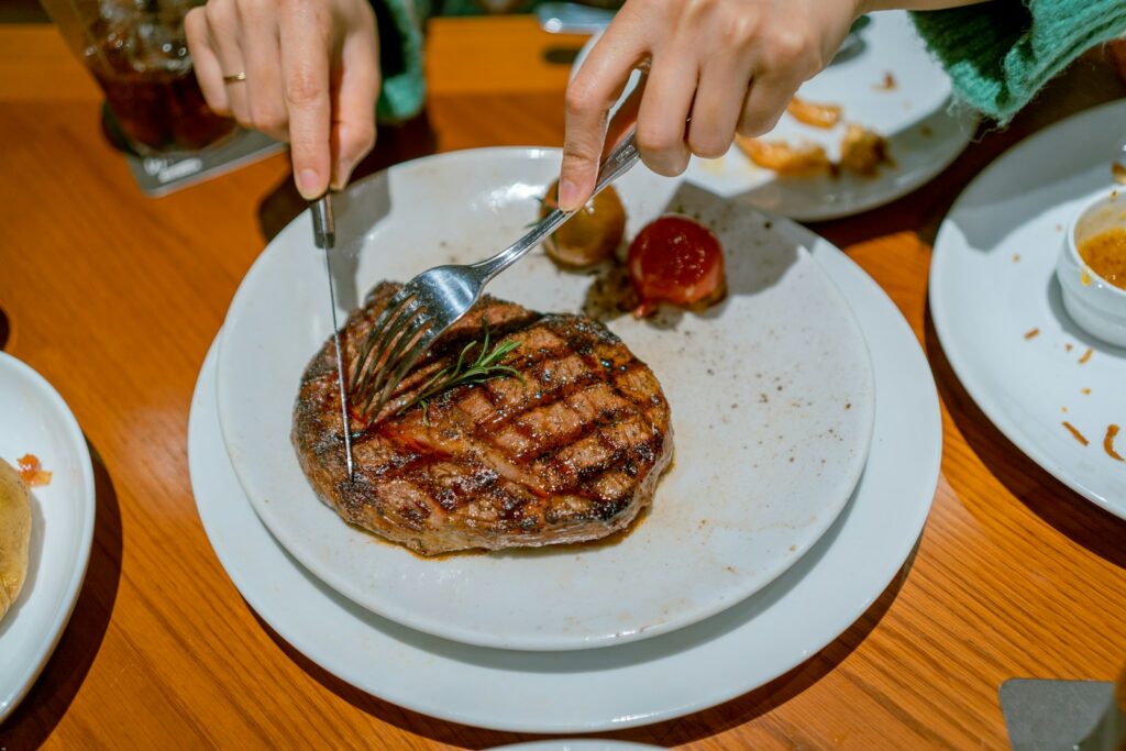 a person cutting into a steak on a plate
