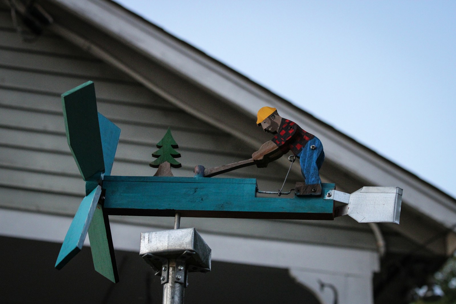 A man working on a wind vane on top of a house