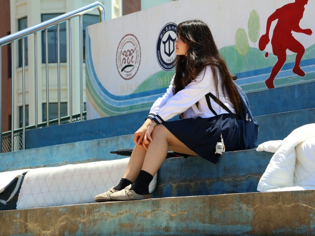 A young woman sits on concrete steps outdoors.