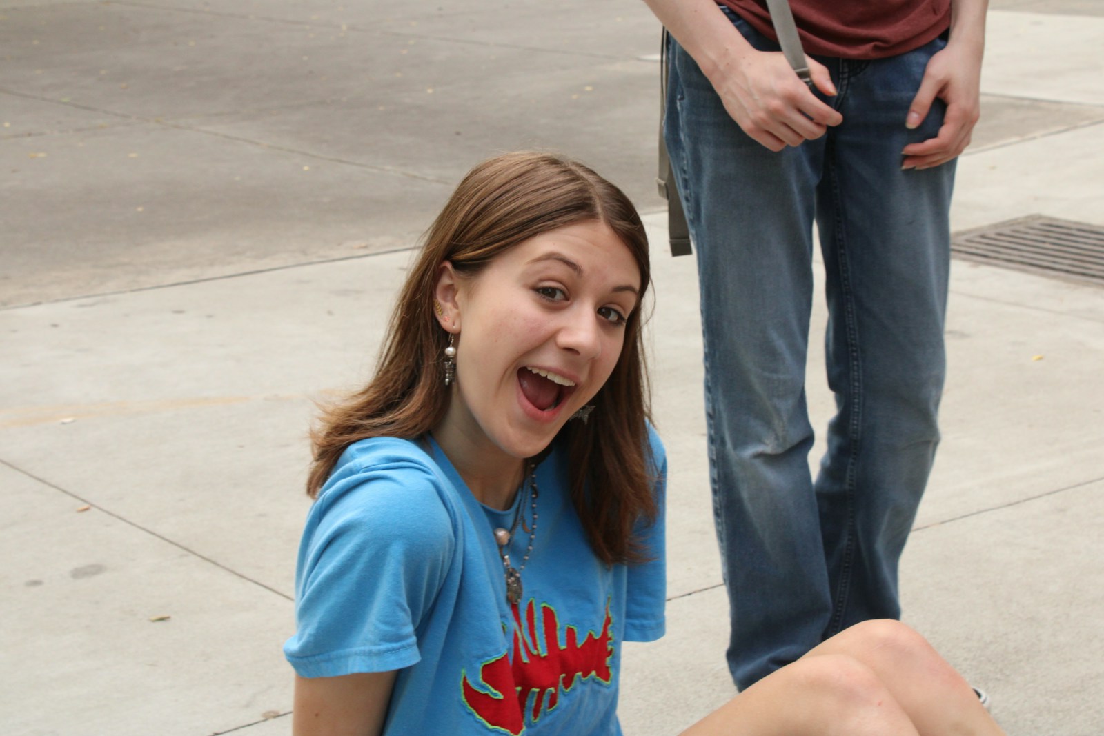 a girl sitting on the ground with a toothbrush in her mouth