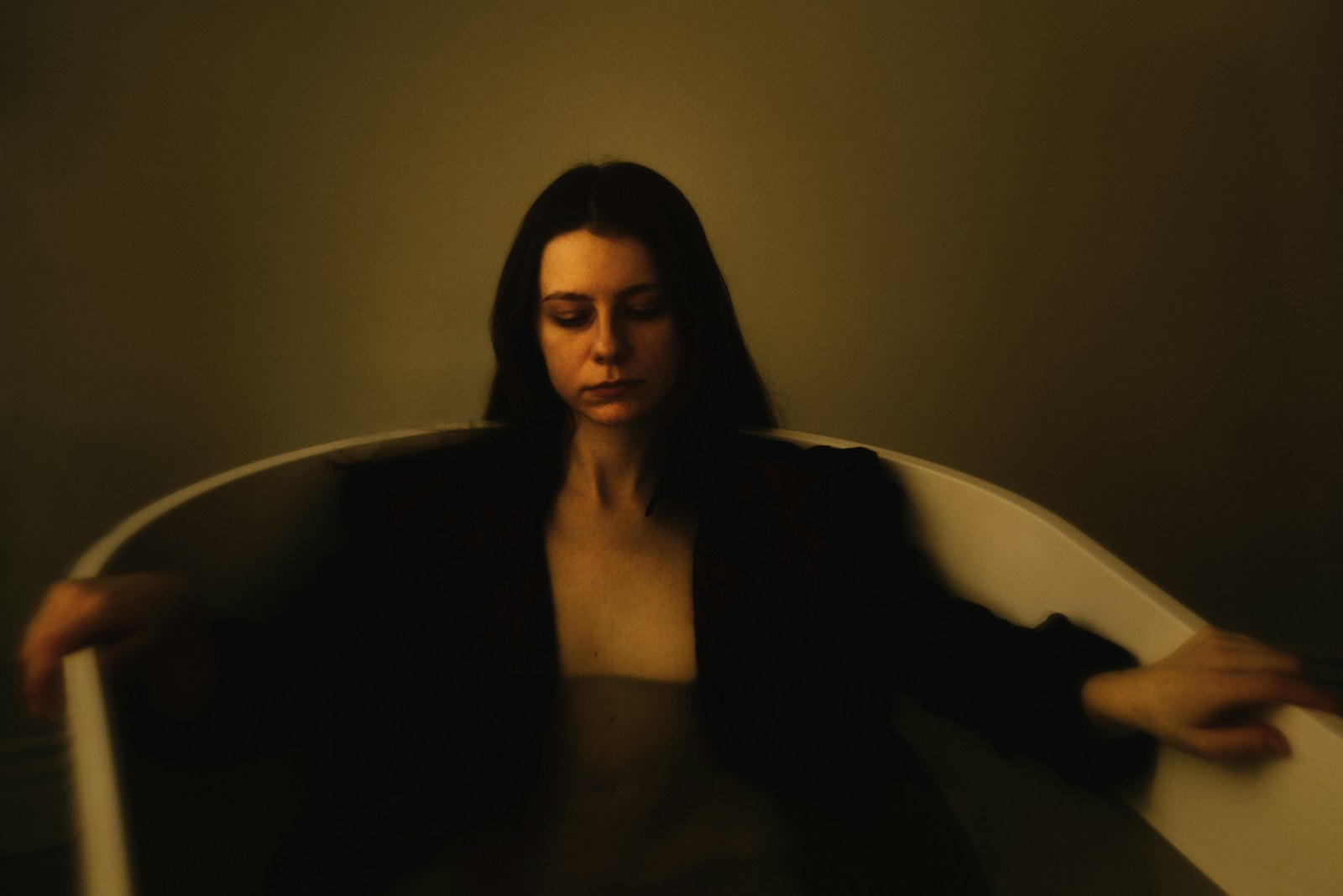 Woman in bathtub wearing a dark jacket