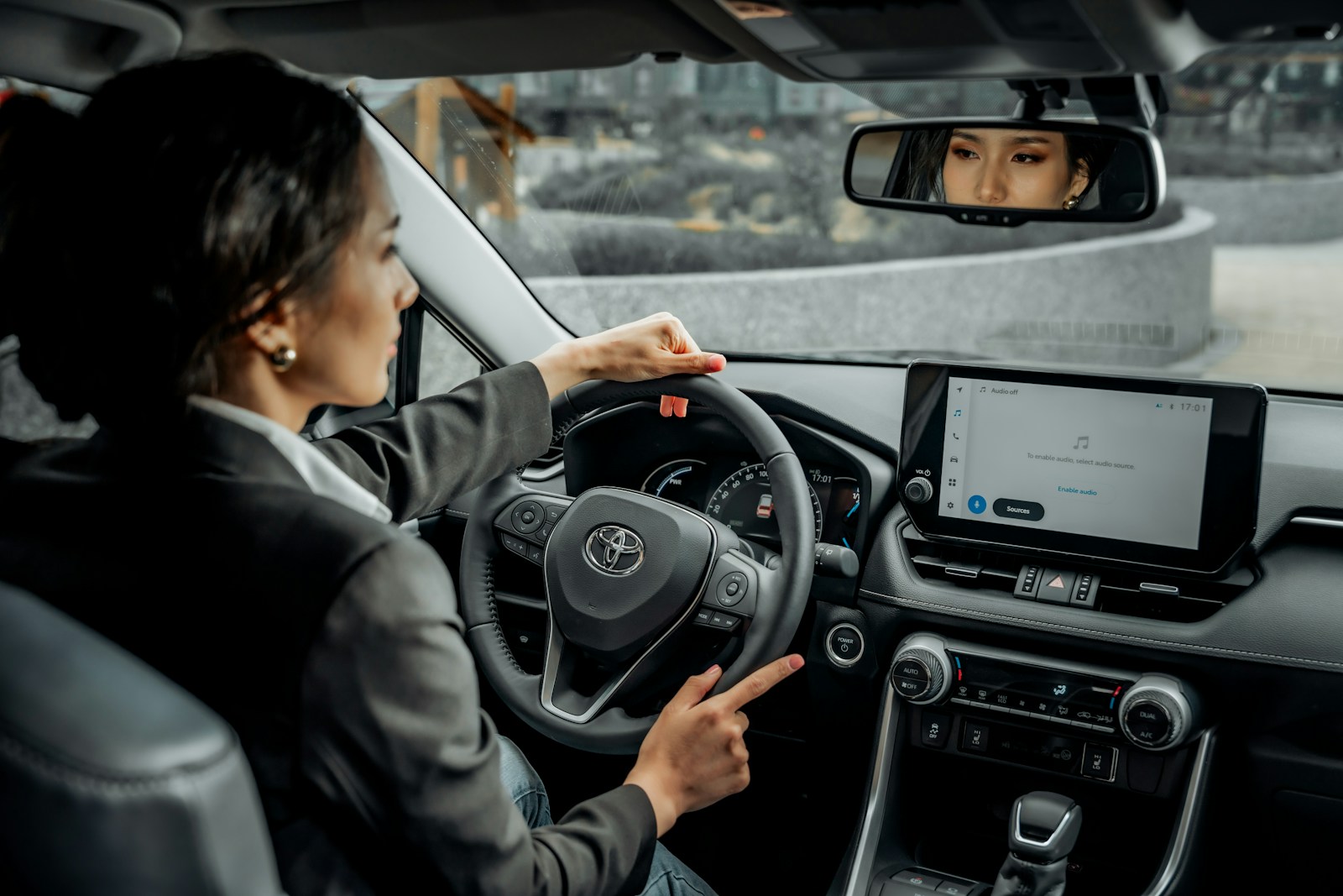 A woman driving a car with a man in the back seat
