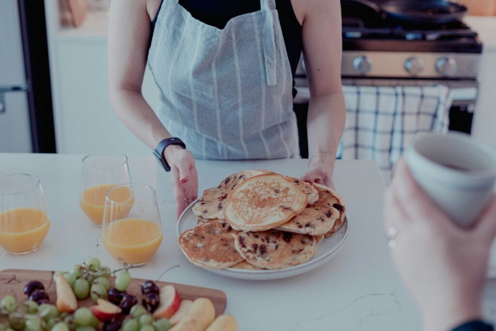 a woman standing in front of a plate of pancakes