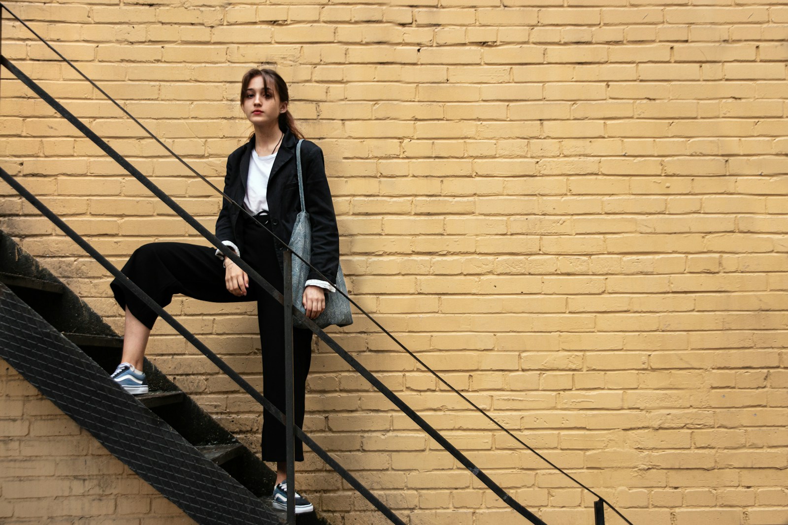 woman in black blazer and black pants standing on stairs
