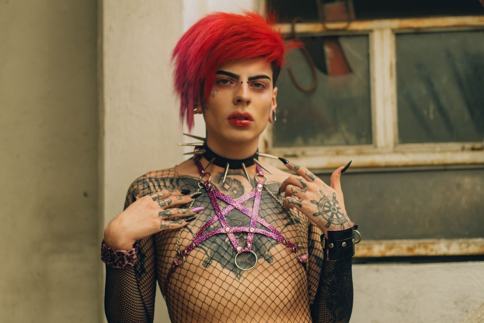 Striking portrait featuring a tattooed individual in unique fashion, set in an urban environment.