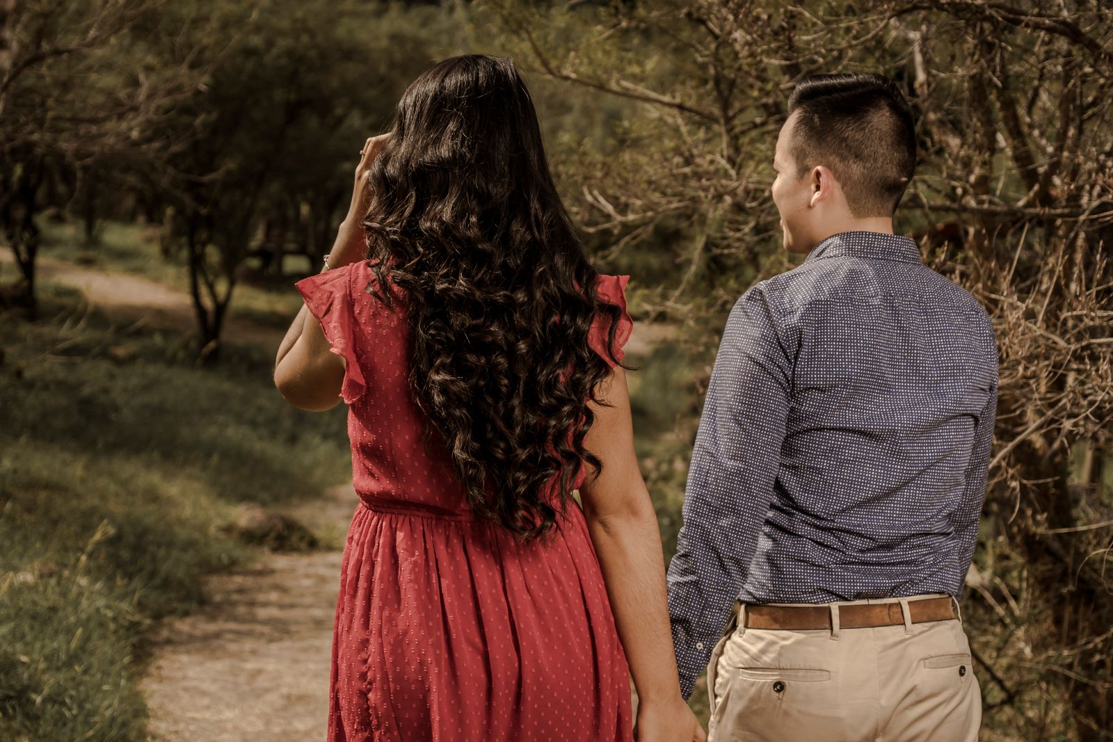 A young couple holding hands and walking on a park path, enjoying a romantic day outdoors.