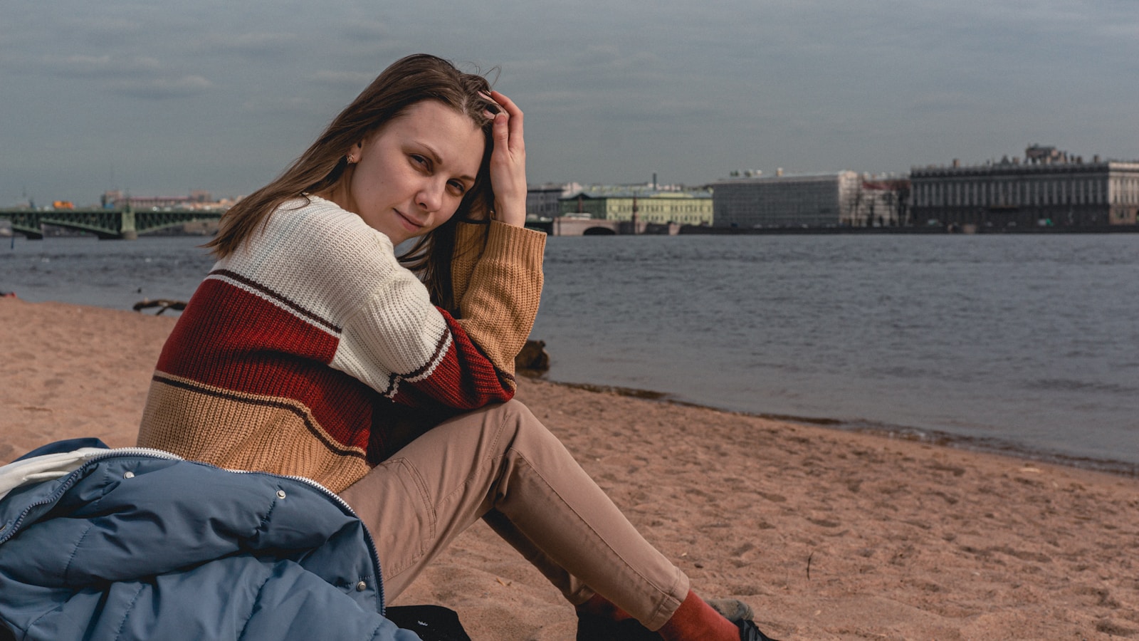 a woman sitting on a beach next to a body of water
