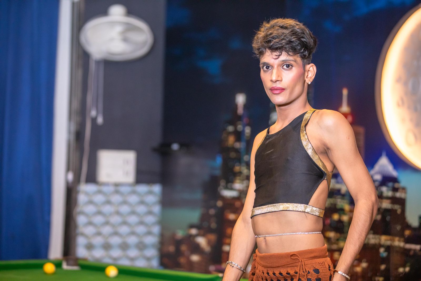 Stylish adult in unique attire posing indoors with an urban backdrop.