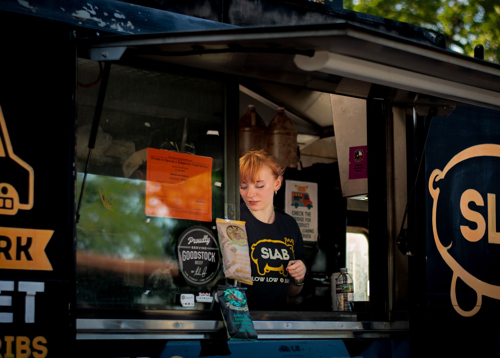 A female vendor serves from a food truck in Austin, TX.