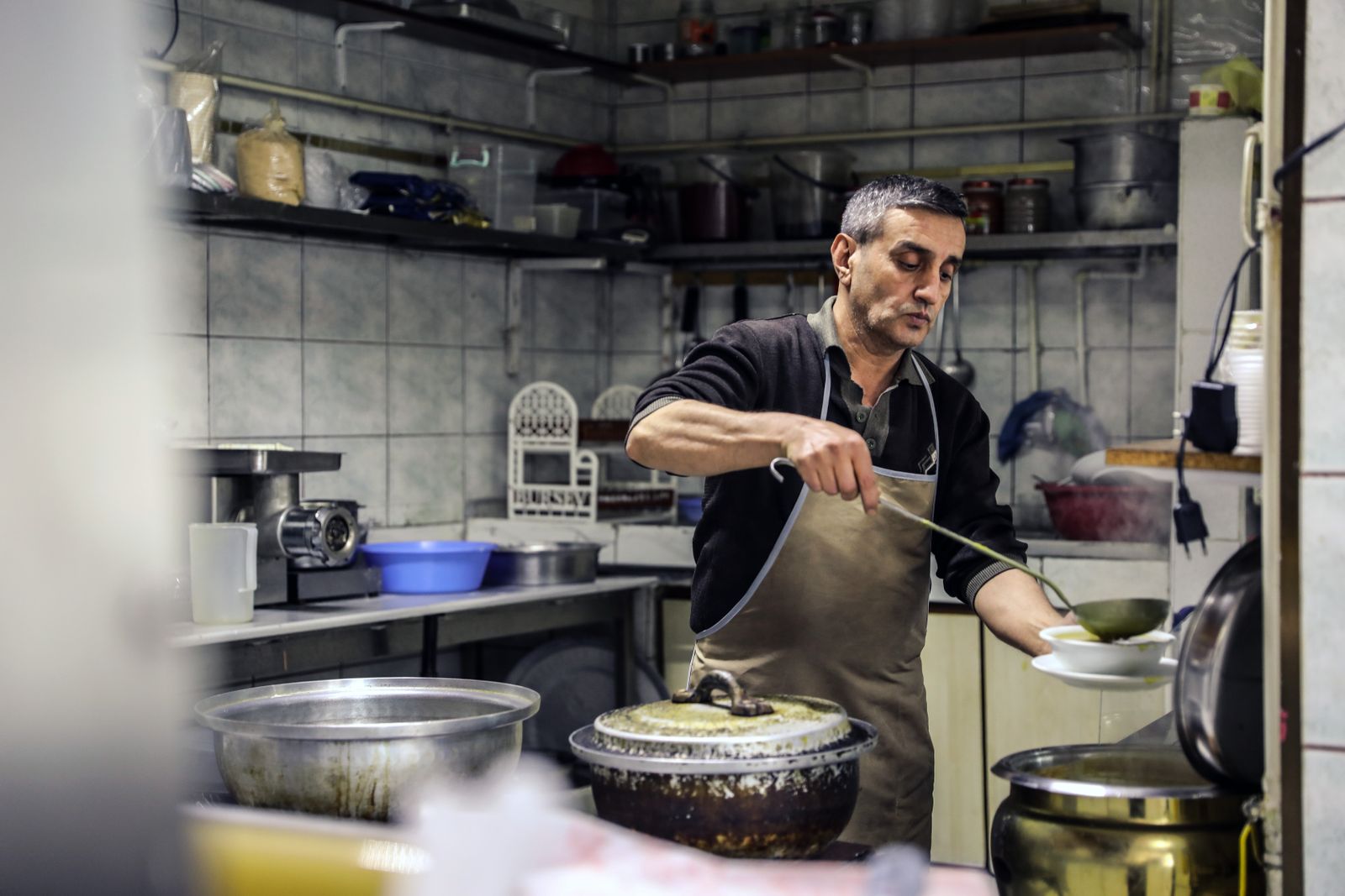 Chef in an apron serving soup in a rustic kitchen setting, creating an authentic dining experience.