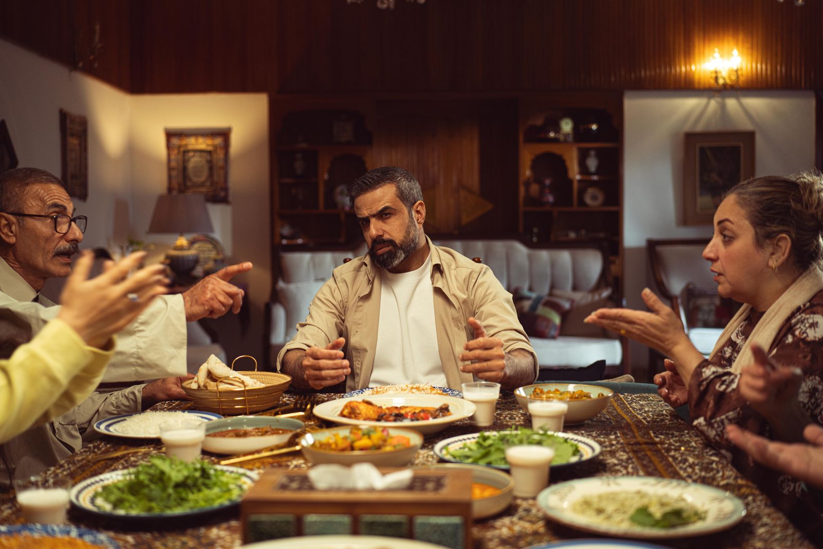 A family gathering during dinner with a lively discussion at an indoor setting, showcasing Middle Eastern cuisine.