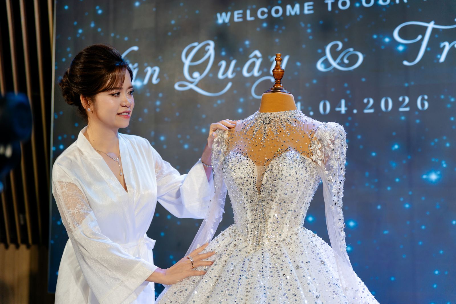 Elegant bride in Hồ Chí Minh admires a dazzling wedding dress against a starry backdrop.