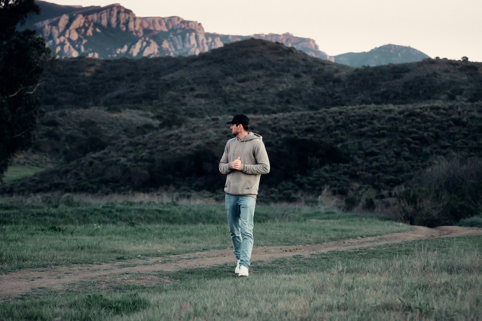 a man standing on a dirt road in a field