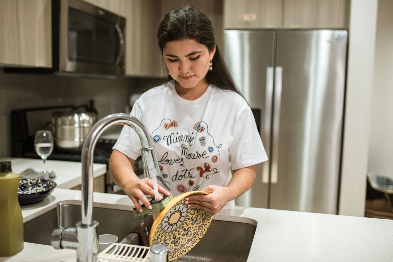 Young woman washing a plate in a modern kitchen sink, showcasing everyday household chores.