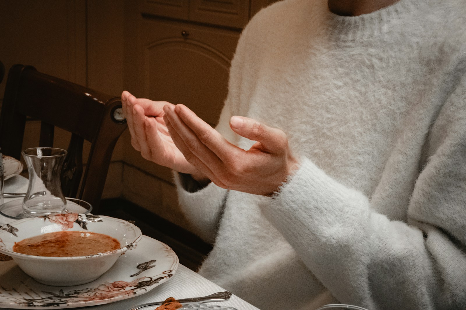 Person in white sweater praying before meal