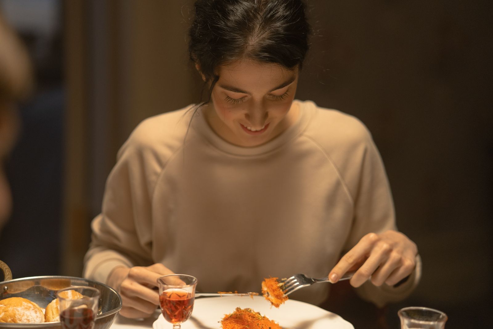A young woman enjoys a festive meal indoors with traditional food and drink.