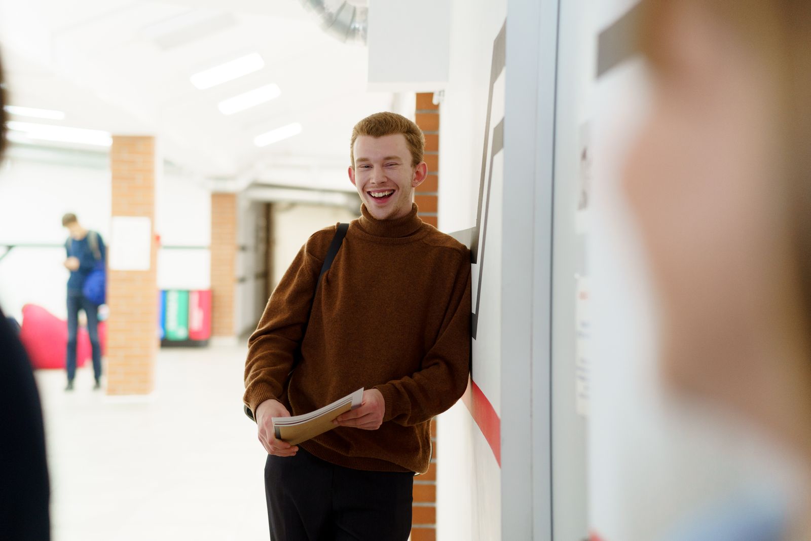 Happy teenage student smiling in a school hallway, holding a notebook. Perfect for education and back-to-school themes.