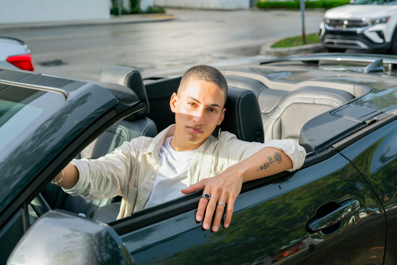 A man sitting in a convertible car in a parking lot
