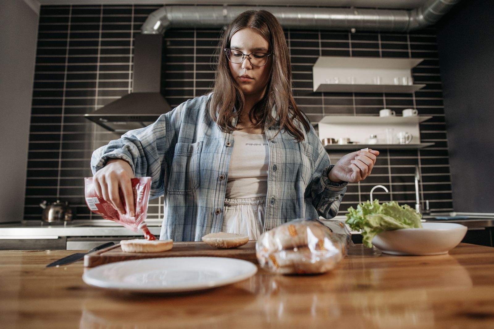 Young woman making a sandwich in a stylish kitchen setting.
